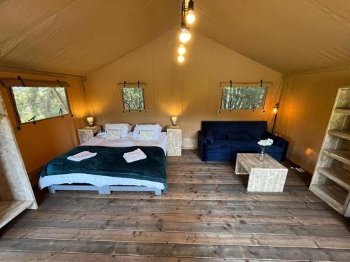 a bedroom in a tent with a bed and a couch at Kingfisher Safari Tent in Droitwich