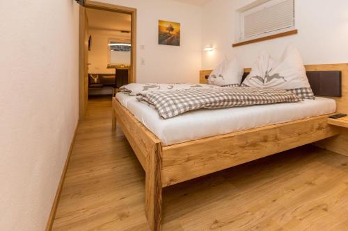 a bedroom with a wooden bed with white sheets at Neue Ferienwohnung in Mittersill mit Grill, Garten und Terrasse in Mittersill