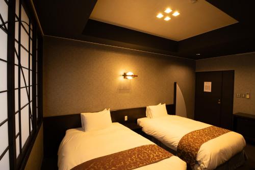 two beds in a hotel room with white sheets at Kikunoya in Miyajima