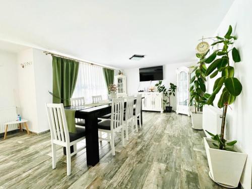 a dining room with a black table and white chairs at Agropa Rooms & Garden Events in Bistriţa