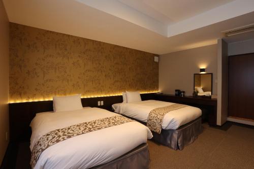 a hotel room with two beds and a mirror at Kikunoya in Miyajima