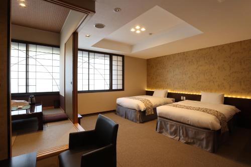 a hotel room with two beds and a desk at Kikunoya in Miyajima