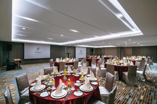 a conference room with tables and chairs and a screen at Holiday Inn Johor Bahru City Centre by IHG in Johor Bahru