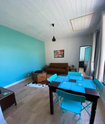 a living room with a table and blue chairs at Studio New-York à Old School à l'ile d'yeu in Port-Joinville