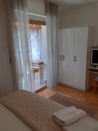 a bedroom with a bed and a window and a television at Guesthouse Apartment Božica in Bol