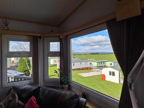 a living room with three windows and a couch at Three Peaks View. in Clitheroe