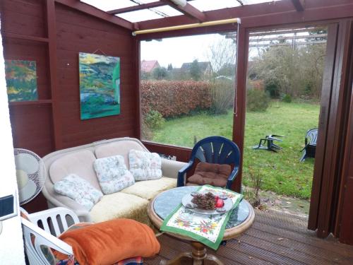 a screened in porch with a couch and a table at Freistehendes Ferienhaus in Adendorf mit Terrasse, Grill und Garten in Adendorf