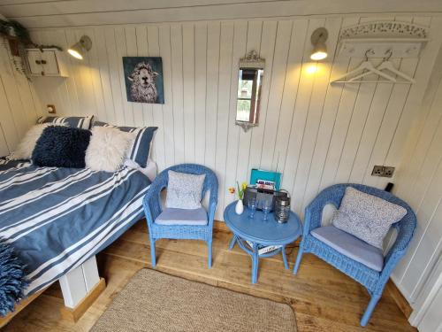 a bedroom with a bed and two chairs and a table at Dolly at Lowlands in Ringwood