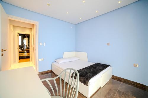 a small bedroom with a white bed and a chair at AuraLux in Agia Triada