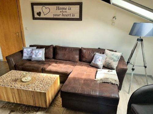 a living room with a brown leather couch and a coffee table at Appartement in Raßreuth mit gemeinsamem Pool, Garten und Grill in Hauzenberg