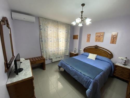 um quarto com uma cama azul, uma mesa e um espelho em Villa Caniles em Caniles