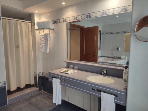 a bathroom with a sink and a large mirror at Hotel Sercotel Cuatro Postes in Avila
