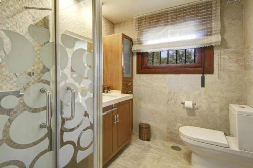 a bathroom with a toilet and a sink at Grand Luxury Villa Piscina & Jacuzzi Granada in Albolote