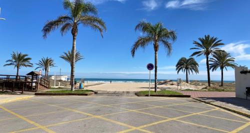 an empty parking lot next to a beach with palm trees at Apartamentos Tugar a 200mts del mar en Playa Gandia in Playa de Gandia