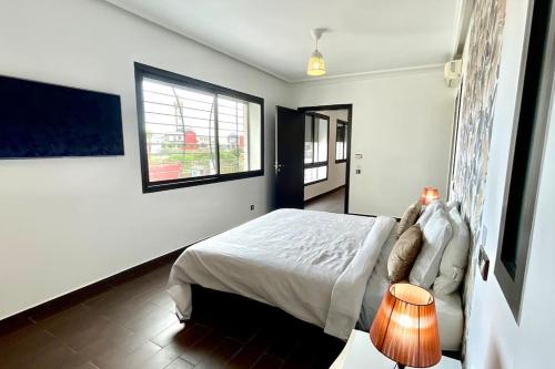 a white bedroom with a bed and a window at Luxury villa with private pool in Casablanca