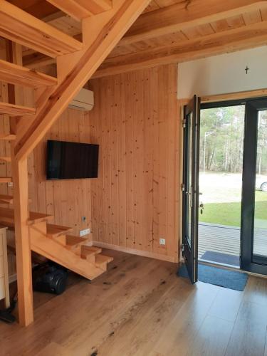 Pokój z drewnianymi ścianami, telewizorem i schodami w obiekcie Domki nad Kukówkiem w mieście Wdzydze Tucholskie