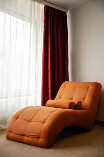 an orange bed in a room with a window at Hotel President in Timişoara