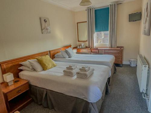 a bedroom with two beds with towels on them at The White Horse Hotel in Leiston