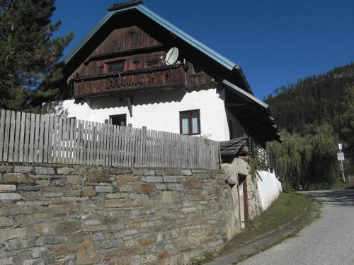 un bâtiment avec une clôture à côté d'un mur en pierre dans l'établissement Haus Tischler Ferienwohnungen, à Ramingstein