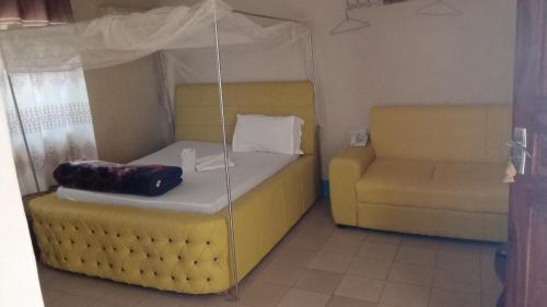 1 dormitorio con 1 cama amarilla y 1 silla en BM. Beach hotel at Nansio, Ukerewe island, en Hamukoko