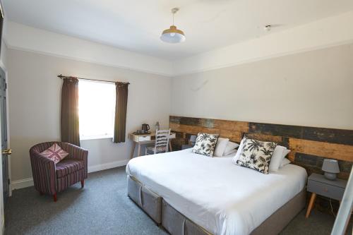 a bedroom with a large bed and a chair at The White Horse Hotel in Leiston