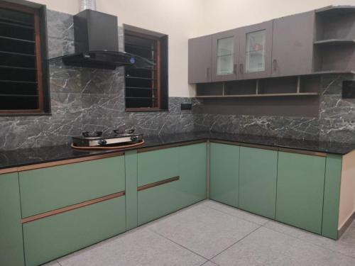 uma cozinha com armários verdes e um balcão preto em Cozy Nest-Fully furnished 3 bedroom property em Alwaye
