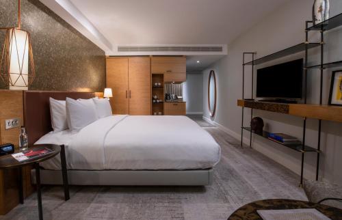 a bedroom with a large bed and a flat screen tv at Lincoln Plaza Hotel London, Curio Collection By Hilton in London