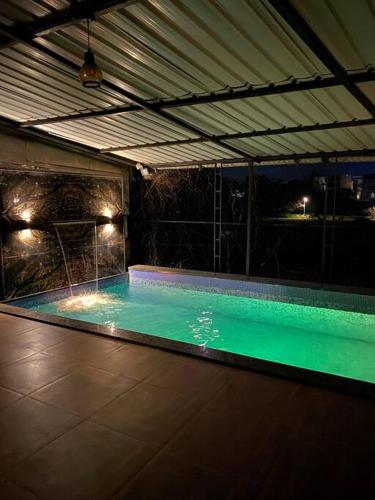 an indoor swimming pool with green water at night at Imagine Harmony in Lonavala