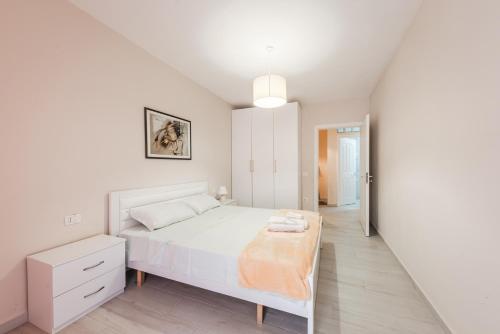 a white bedroom with a bed and a table at Helia's Cozy Apartment Qerret in Golem