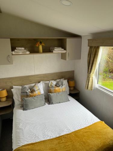 a bedroom with a white bed with pillows and a window at Platinum caravan holidays in Port Seton