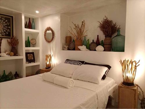 a bedroom with a white bed and shelves with vases at Balay Asiano Cabin in Puerto Princesa City