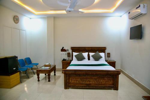 a bedroom with a bed and a tv and chairs at SWAT HOTEL in Mingora