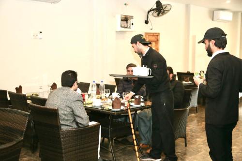 a man holding a cake on a tray in a restaurant at SWAT HOTEL in Mingora