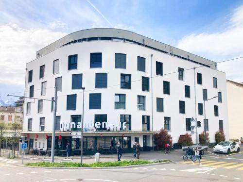 un edificio blanco con un cartel en la parte delantera en Nonanteneuf Appart-hôtel - Aigle en Aigle