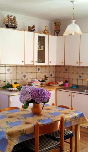 una mesa de cocina con un jarrón de flores púrpuras. en Appartement in Barano d Ischia mit schöner Terrasse, en Isquia