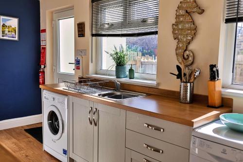 a kitchen with a sink and a washing machine at Finest Retreats - Byron Street in Amble