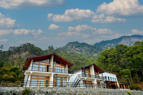 two houses on a hill with mountains in the background at Silver fern by the Hillside in Nainital