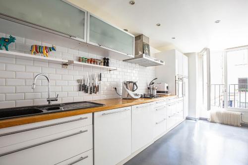 a kitchen with white cabinets and a sink at Veeve - Chic By Bonne-Nouvelle in Paris