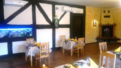 a dining room with tables and chairs and a fish tank at Hotel Stawisko Klaudyn in Klaudyn