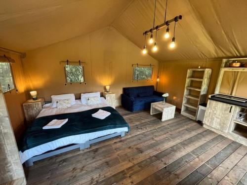 a bedroom in a tent with a bed and a couch at Teal Safari Tent in Droitwich