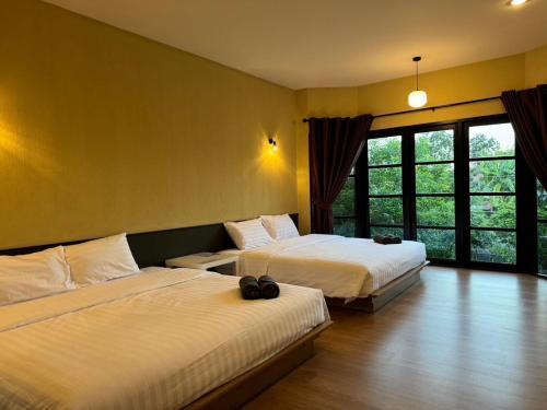 a bedroom with two beds and a large window at Morimei Khaoyai in Ban Khlong Yang