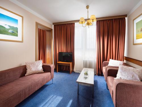 Hotel Cernigov في هراديك كرالوف: غرفة معيشة مع كنبتين وتلفزيون
