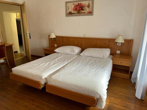 una camera da letto con un grande letto con due comodini di Ristorante Bar Pensione Novaggio a Novaggio