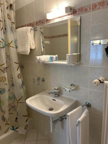 La salle de bains est pourvue d'un lavabo et d'un rideau de douche. dans l'établissement Ristorante Bar Pensione Novaggio, à Novaggio