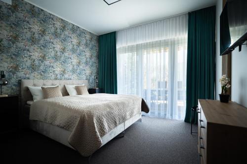 um quarto com uma cama e uma grande janela em Villa Sinaloa-Spa em Ruda Śląska