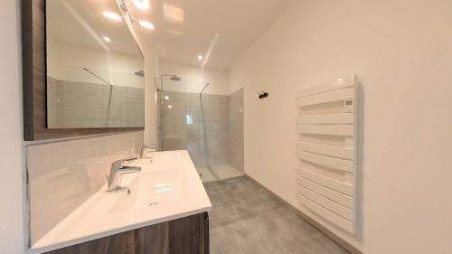 une salle de bain blanche avec un lavabo et un miroir dans l'établissement Spacious 2 bedroom Apartment with Garden Near Pezenas, à Nézignan-lʼÉvêque