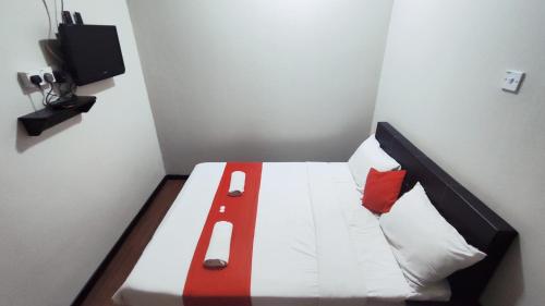 a small bedroom with a bed with red and white pillows at Hotel Rasa Sayang 2 in Tanah Rata