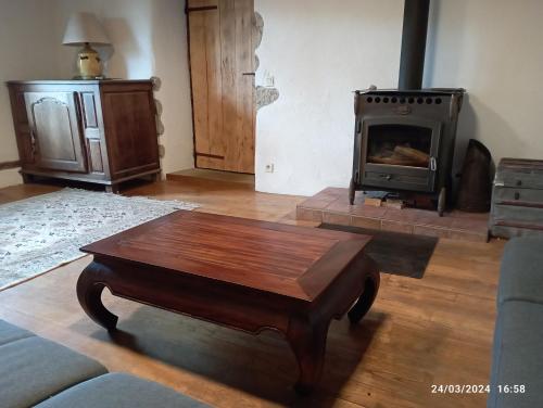 a living room with a wooden coffee table and a stove at Roseland, retraite calme en pleine nature in Saint-Girons