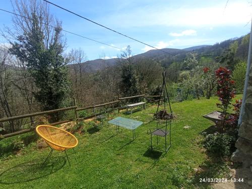 a garden with two chairs and a bench in the grass at Roseland, retraite calme en pleine nature in Saint-Girons