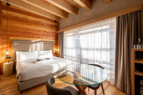 a bedroom with a bed and a glass table at Au Charmant Petit Lac - Ecohotel Parc & Spa in Champoluc